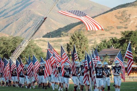 Taken by Natalie Marvin, football players carry flag onto the field to honor Veterans in their game on August 26th. 